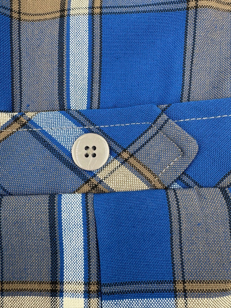 Close-up of a plaid shirt with a button on a blue, gray, and beige fabric.